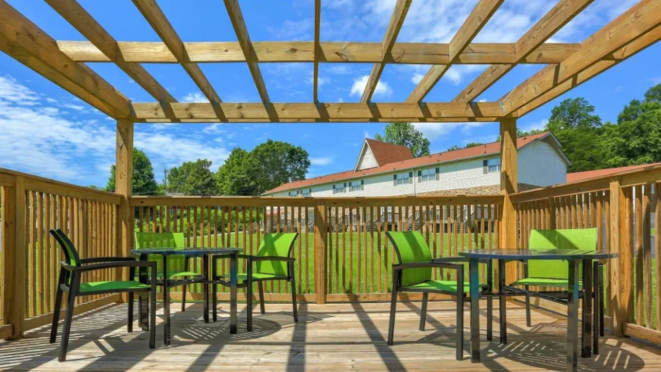 a patio with green chairs and a pergol at The Country Oaks Apartments