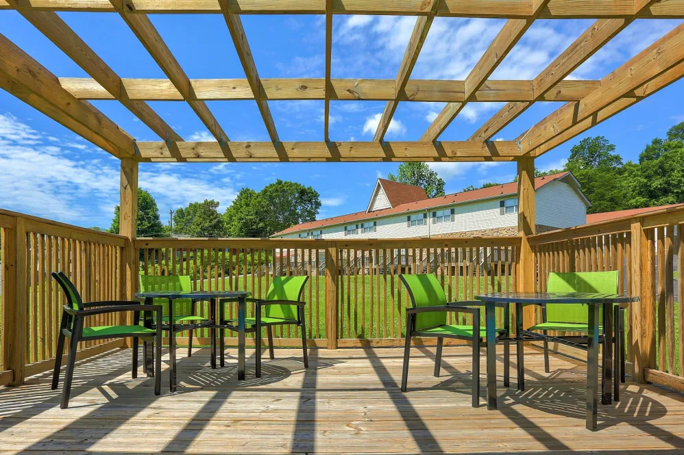 a patio with green chairs and a pergol at The Country Oaks Apartments