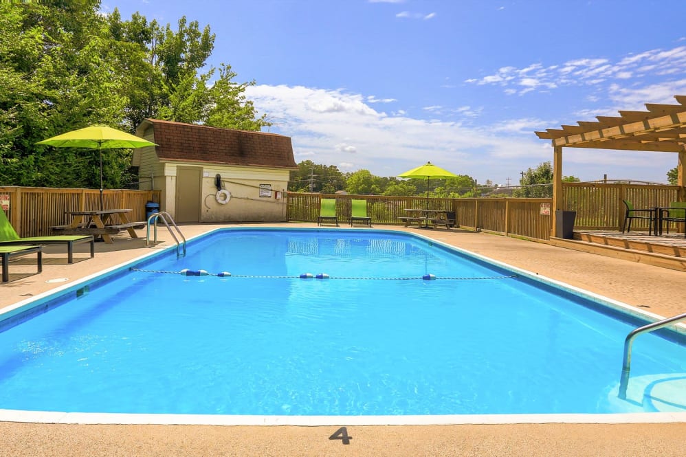 a pool with a sun lounger and umbrella at The Country Oaks Apartments